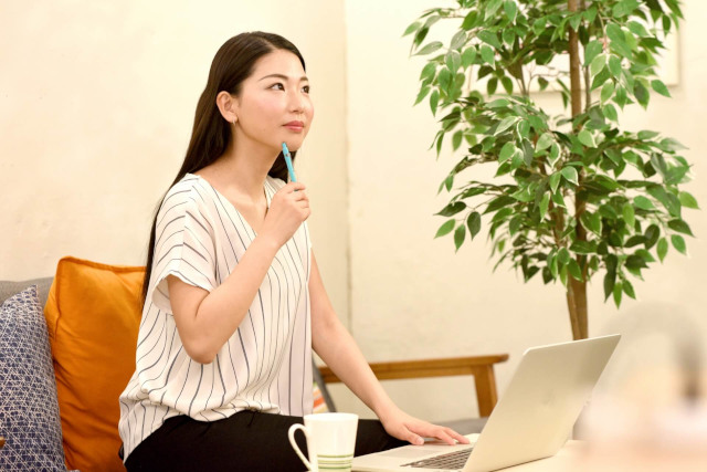 パソコンを使用しながら考える女性